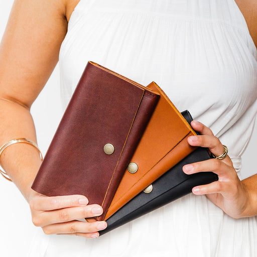 Three Rancher Wallets in Cognac, Honey, and Black held by a person against a white background. featured image