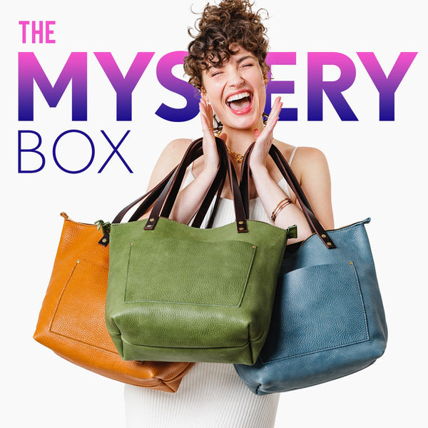 Model holding three colorful leather tote bags. Text reads: "The Mystery Box"