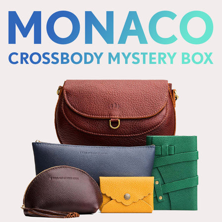 Monaco Crossbody in Nutmeg next to Utility Bag, Taco Tassel Pouch, Daisy Plus Wallet, and a Leather Wrap Journal. Text reads "Monaco Crossbody Mystery Box"