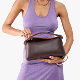 Grizzly | Model holding a dark smooth brown colored bowler style hand bag
