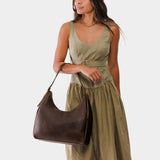 Coldbrew Large | Model holding u-shaped, flat-bottomed leather shoulder bag with adjustable strap