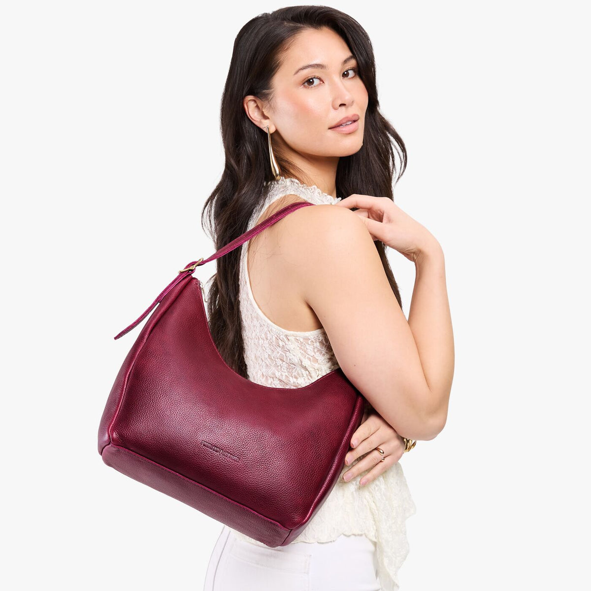 Orchid*Medium | Model holding u-shaped, flat-bottomed leather shoulder bag with adjustable strap