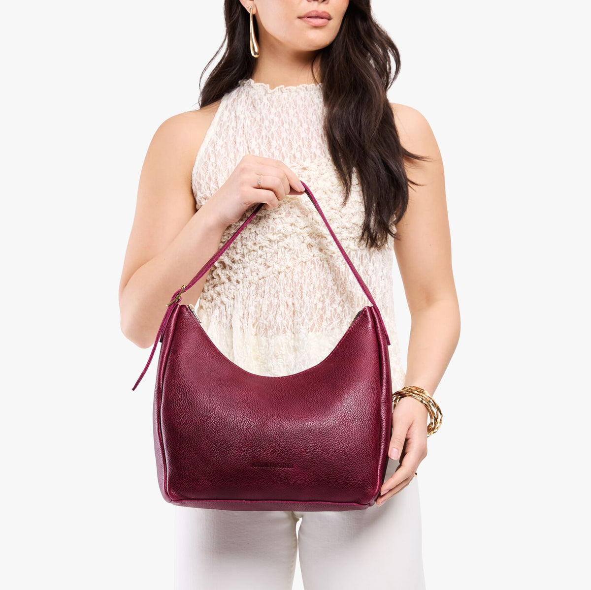 Orchid*Medium | Model holding u-shaped, flat-bottomed leather shoulder bag with adjustable strap