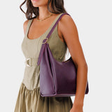 Plum Medium | Model holding u-shaped, flat-bottomed leather shoulder bag with adjustable strap