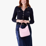 Pinkaboo Small | Model holding symmetrical bucket bag with handle, latch closure, and removable crossbody strap