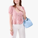 Skyway Small | Model carrying symmetrical bucket bag with handle, latch closure, and removable crossbody strap