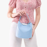 Skyway Small | Model holding symmetrical bucket bag with handle, latch closure, and removable crossbody strap