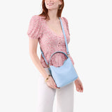 Skyway Small | Model wearing symmetrical bucket bag with handle, latch closure, and removable crossbody strap
