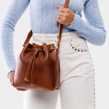 Nutmeg Small | Model holding slouchy crossbody bag with drawstring closure