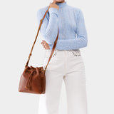 Nutmeg Small | Model holding slouchy crossbody bag with drawstring closure