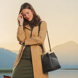 Black | Model wearing symmetrical bucket bag with latch closure and removable crossbody strap
