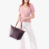 Larkspur Zipper | Model holding large leather tote bag with sturdy bridle handles and front pocket