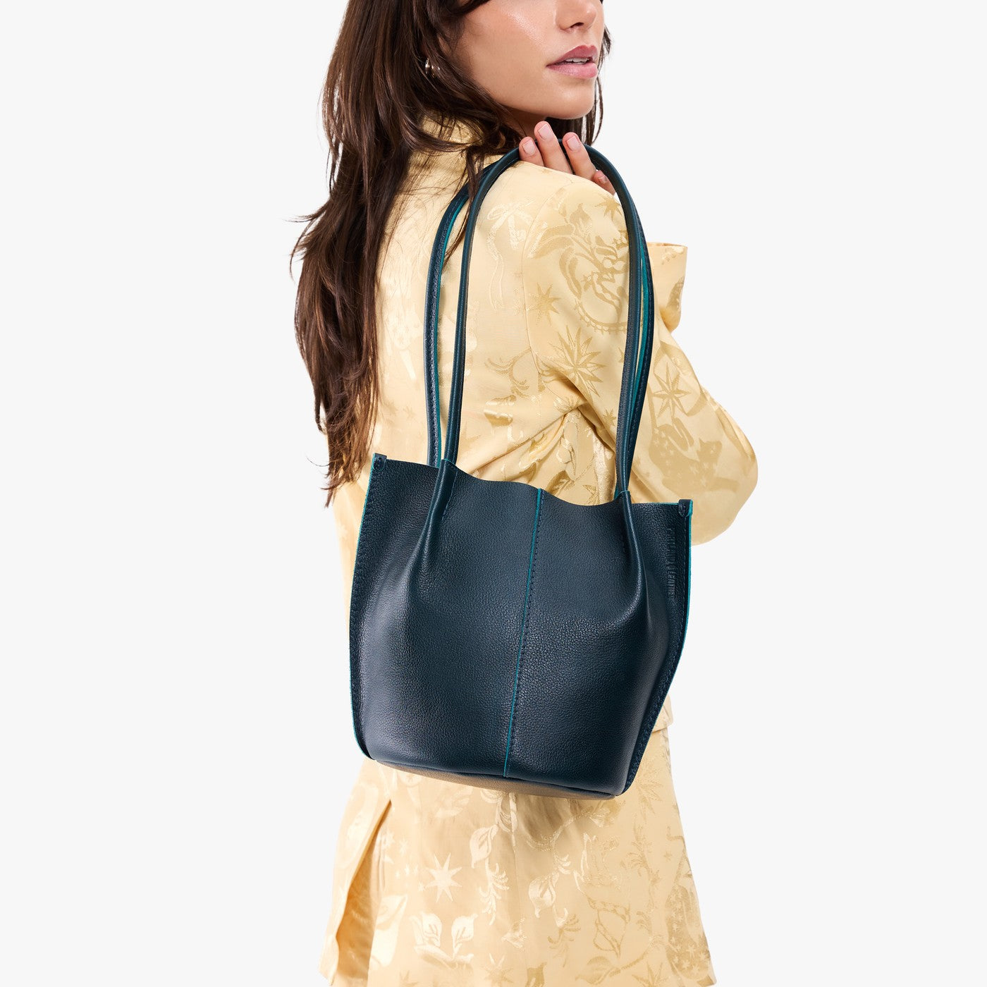 Boreal*Classic | Model wearing matching light yellow shirt and trousers carrying petite bucket shaped tote bag with matching leather handles