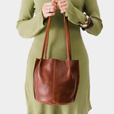 Nutmeg Small | Model wearing light green dress holding petite bucket shaped tote bag with matching leather handles