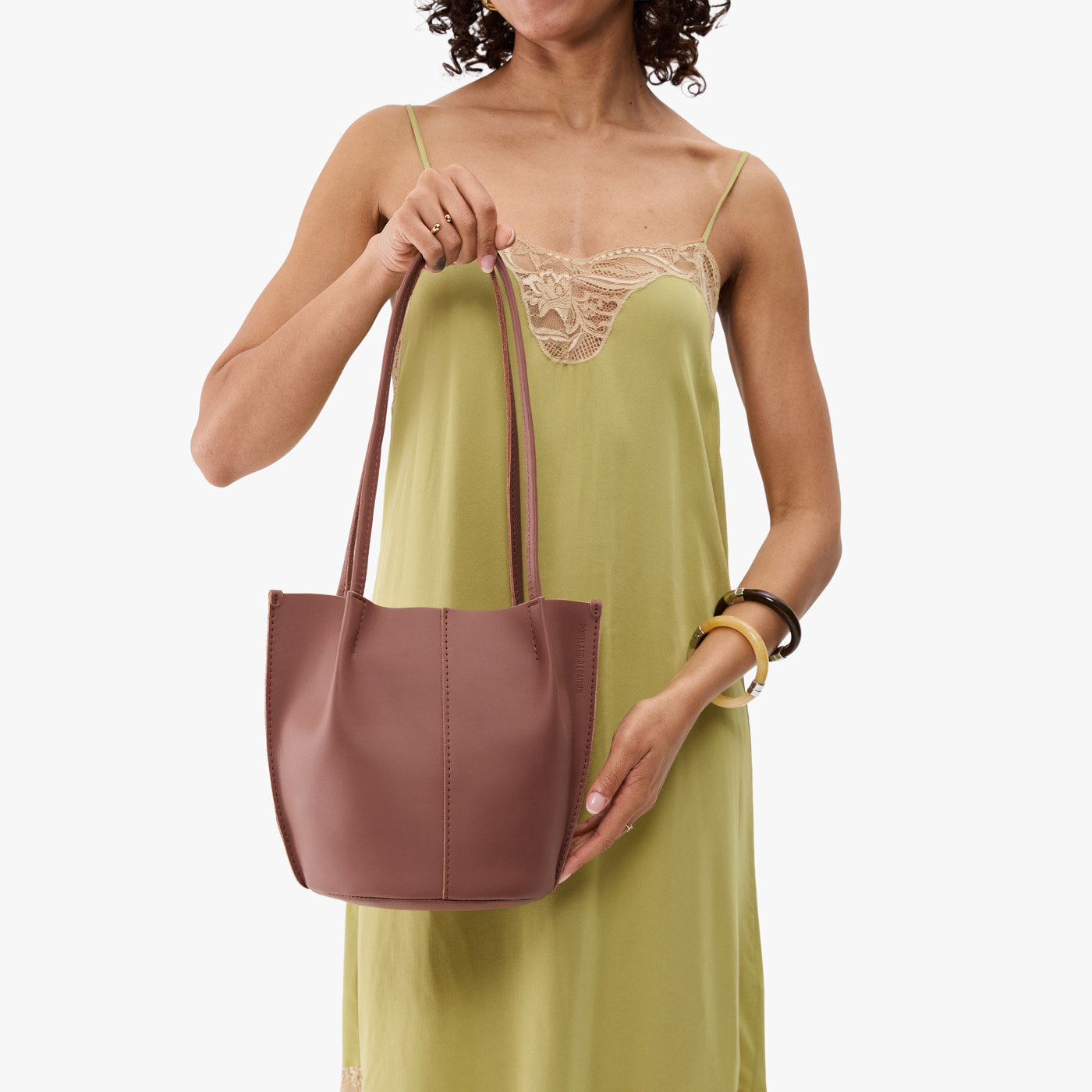 Sunkissed*Classic | Model wearing sleeveless light green dress holding petite bucket shaped tote bag with matching leather handles