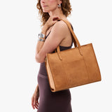 Desert Flower | Model carrying structured wide embossed leather tote bag with overlapping panels and crossbody strap