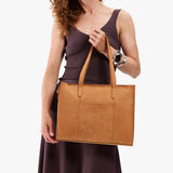 Desert Flower | Model holding structured wide embossed leather tote bag with overlapping panels and crossbody strap