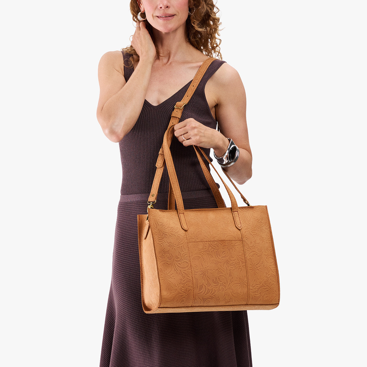 Desert Flower | Model carrying structured wide embossed leather tote bag with overlapping panels and crossbody strap
