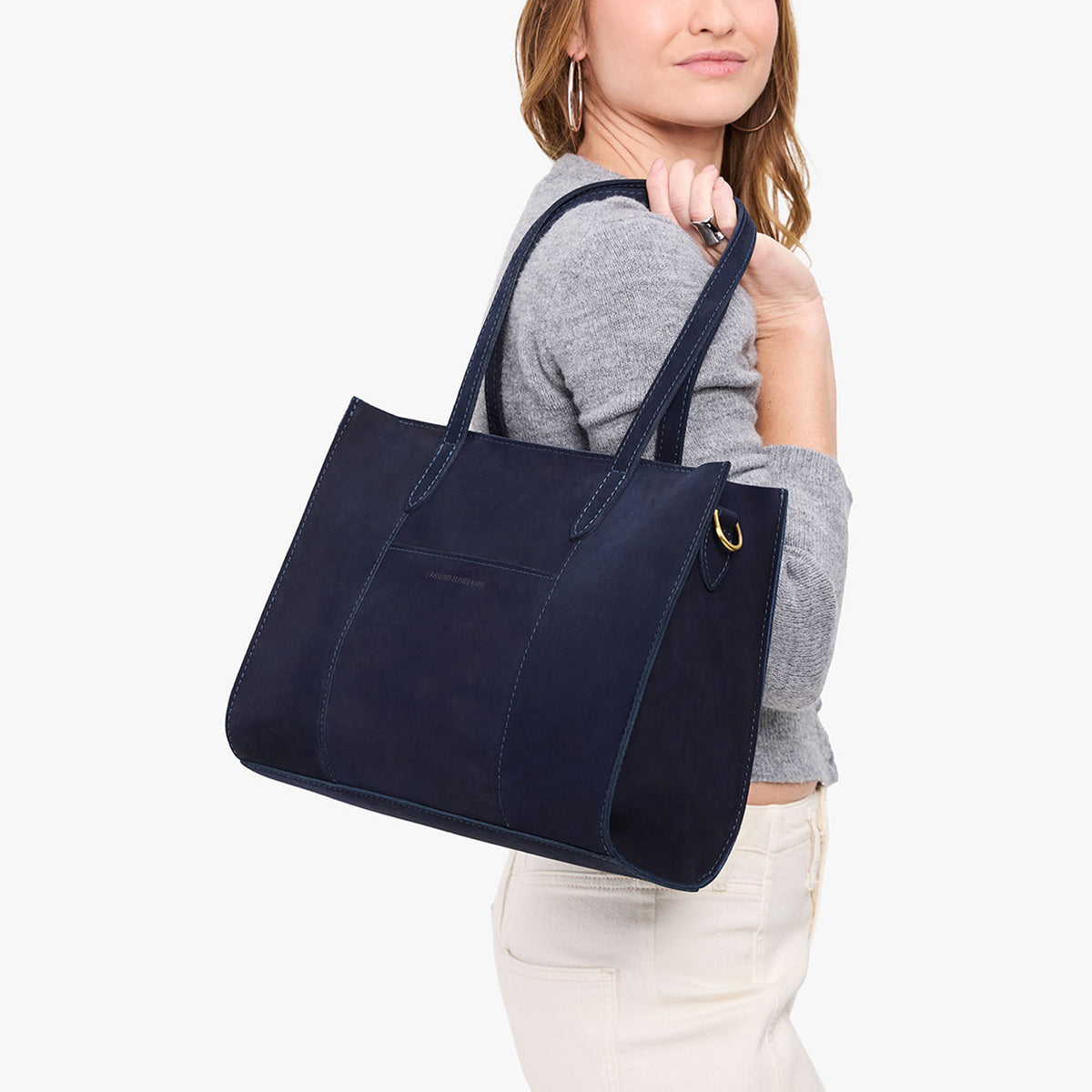 Velvet Blue*East/West | Model holding structured wide tote bag with overlapping panels and crossbody strap