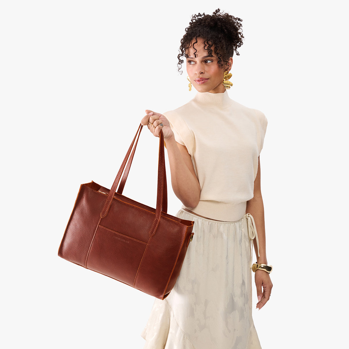 Nutmeg*Oversized East/West | Model holding structured wide tote bag with overlapping panels and crossbody strap