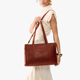 Nutmeg Oversized East/West | Model holding structured wide tote bag with overlapping panels and crossbody strap