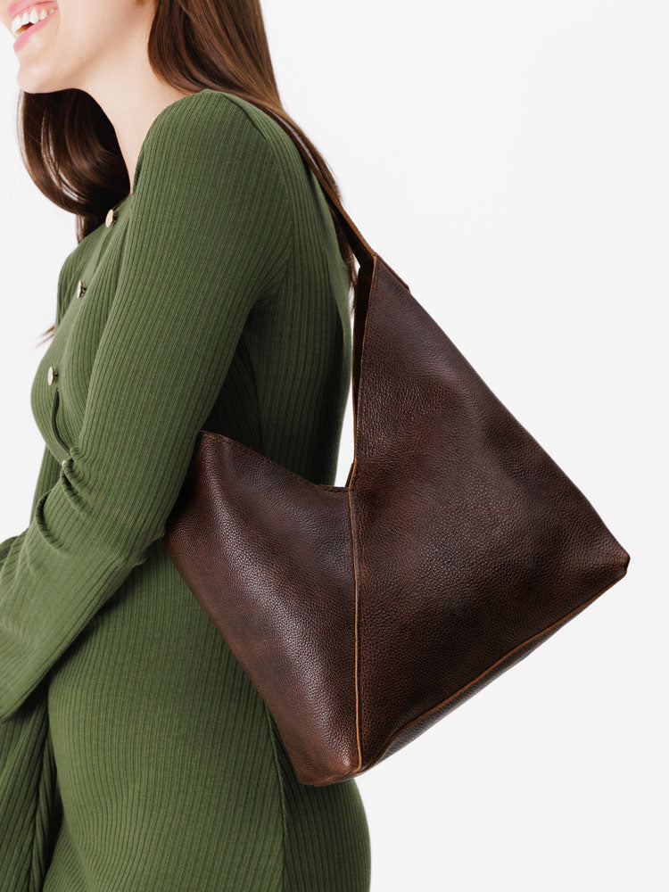 Woman wearing a green dress with a brown leather handbag on a white background