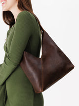 Woman wearing a green dress with a brown leather handbag on a white background