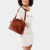 Nutmeg Large | Model holding symmetrical leather bag with leather drawstring closure and adjustable shoulder strap