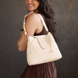 Pebbled Bone Large | Model holding symmetrical leather bag with leather drawstring closure and adjustable shoulder strap