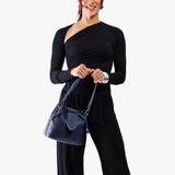 Cobalt Small | Model holding symmetrical leather bag with leather drawstring closure and adjustable shoulder strap