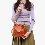 Sienna Small | Model holding symmetrical leather bag with leather drawstring closure and adjustable shoulder strap