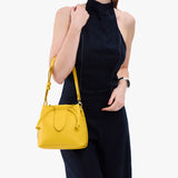 Canary Small | Model holding symmetrical leather bag with leather drawstring closure and adjustable shoulder strap