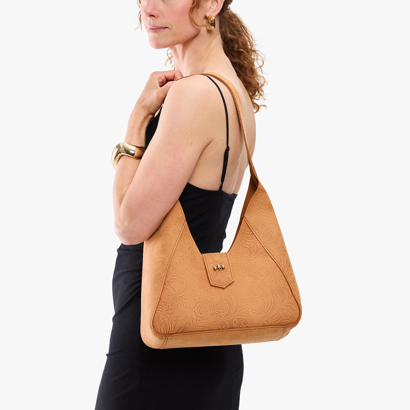 Desert Flower | Model carrying structured hobo shoulder bag with floral patterned embossed leather, adjustable strap and magnetic closure
