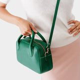 Bacalar Large | A large bowler styled bag with a crossbody strap being worn by a model in a white knit top