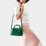 Bacalar Large | A large bowler styled bag with a crossbody strap being worn by a model in a white knit top