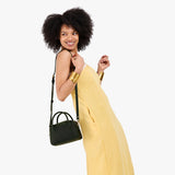 Evergreen Small | A bowler styled bag with a crossbody strap being worn by a model in a yellow dress