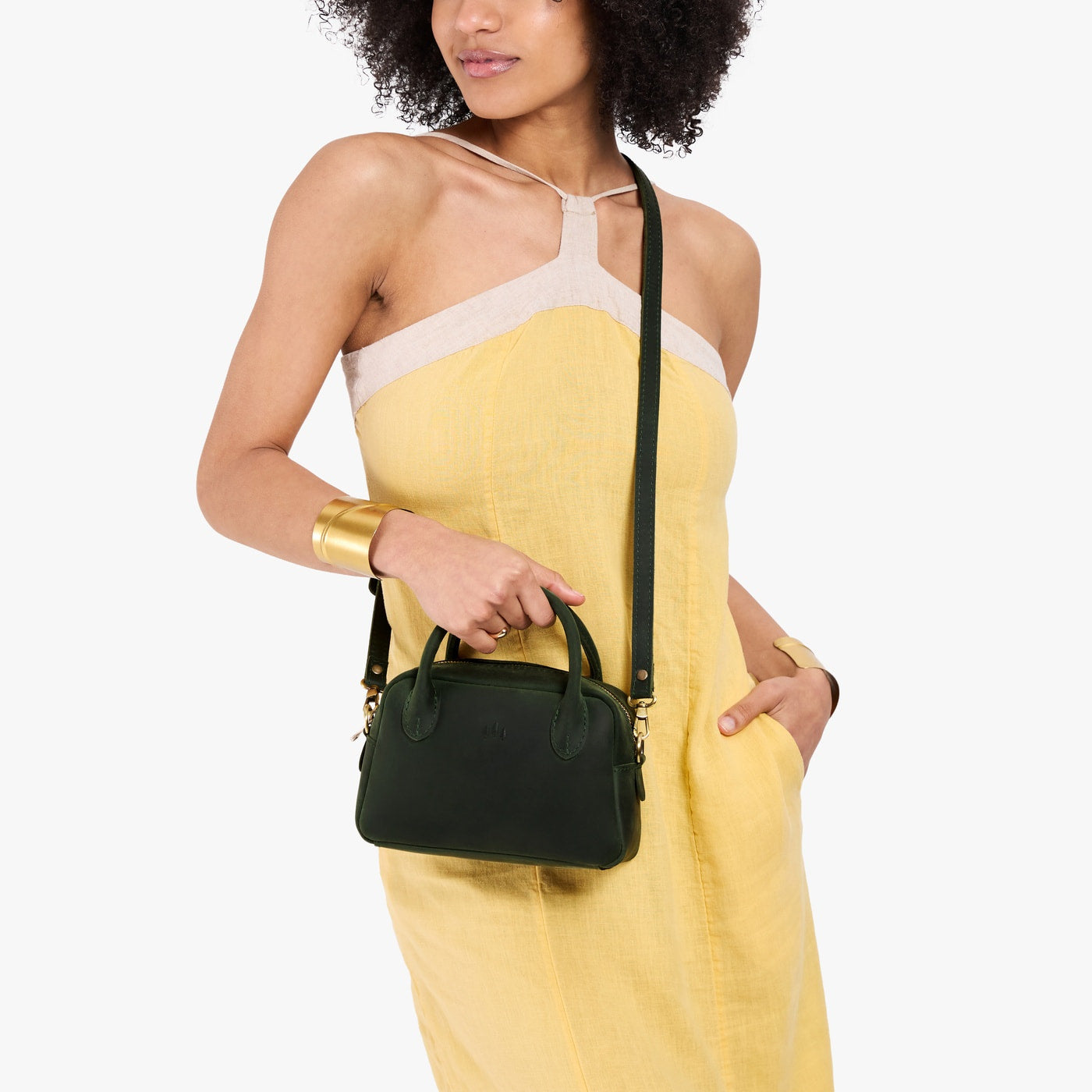 Evergreen*Small | A bowler styled bag with a crossbody strap being worn by a model in a yellow dress