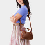 Nutmeg Small | A Bowler style purse with a crossbody strap being worn by a model