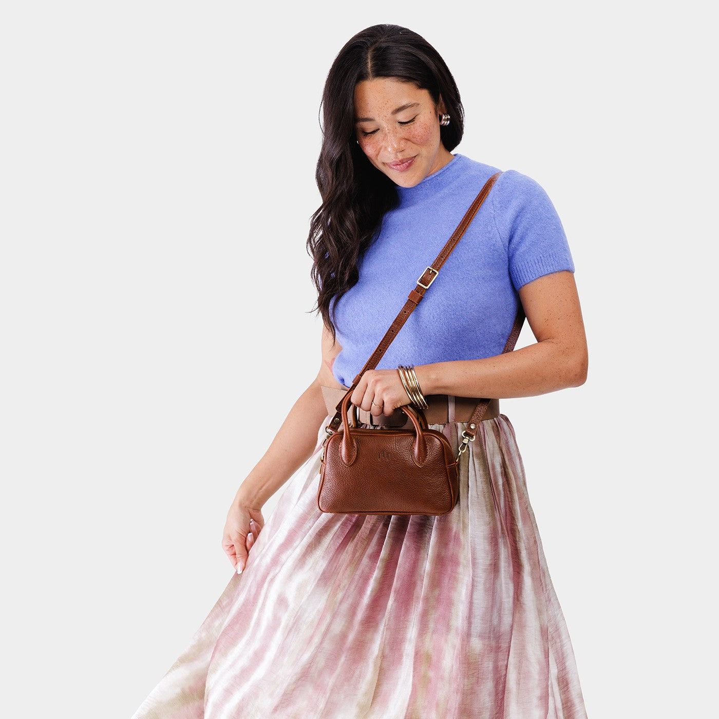 Nutmeg*Small | A Bowler style purse with a crossbody strap being worn by a model