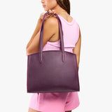 Plum Large | Model carrying leather tote bag with handles, adjustable crossbody strap, and two back pockets