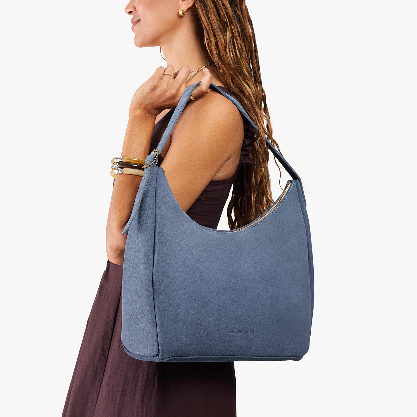 Denim*Large | Model holding u-shaped, flat-bottomed leather shoulder bag with adjustable strap