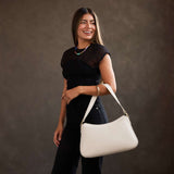 Bone Large | Model holding a bean shaped shoulder bag with a zipper closure
