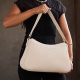 Bone Large | Model holding a bean shaped shoulder bag with a zipper closure