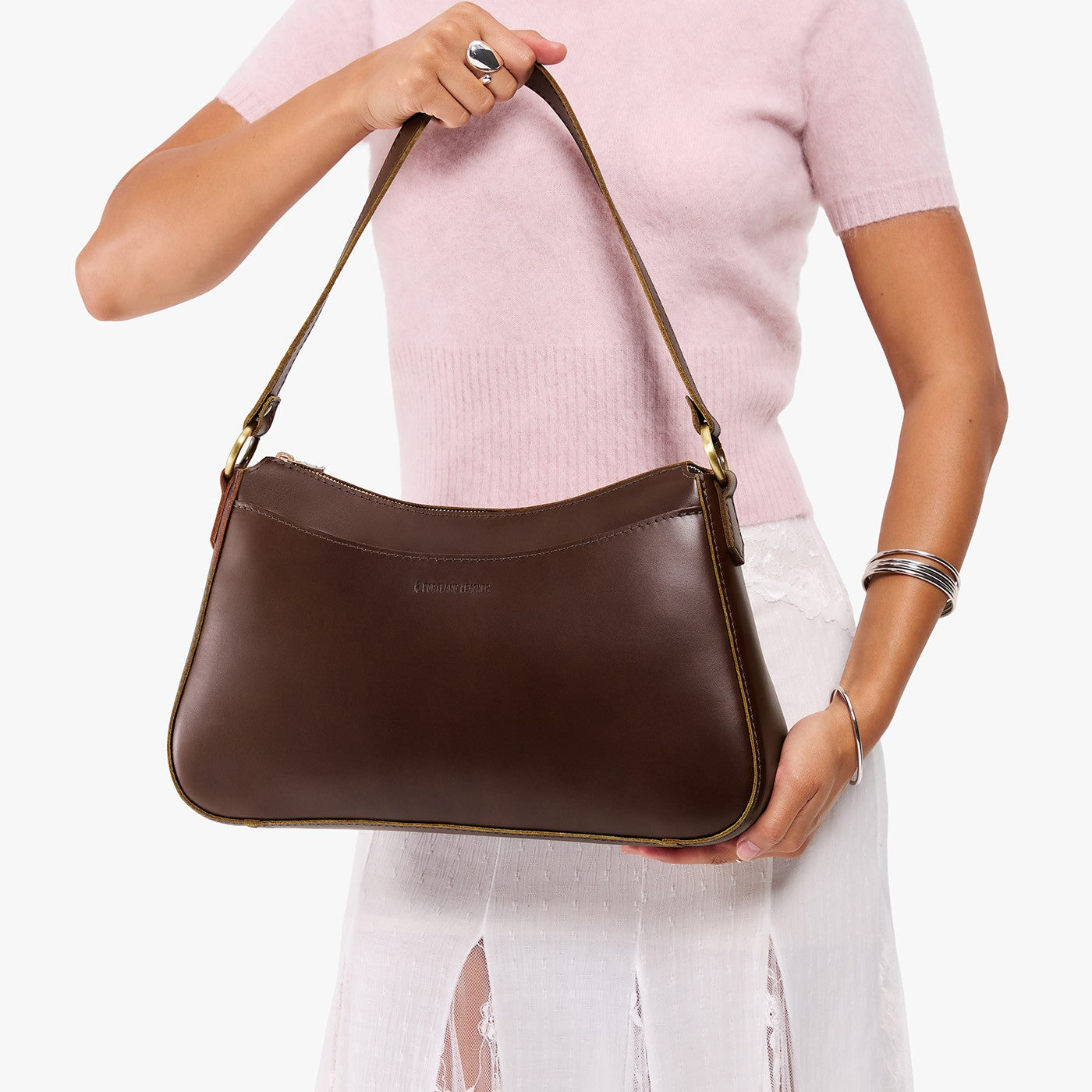 Chocolate Brown*Large | Model holding a bean shaped shoulder bag with a zipper closure