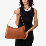 Honey Large | Model holding a bean shaped shoulder bag with a zipper closure