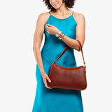 Nutmeg Large | Model holding a bean shaped shoulder bag with a zipper closure