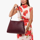Cabernet Large | Model holding a triangular shoulder bag with antiqued brass finished 