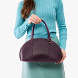 Larkspur Small | Model holding a half circle crossbody bag with handles and removable crossbody strap 