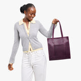 Larkspur North/South | Model holding structured large tote bag with overlapping panels and crossbody strap