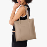 Stone North/South | Model holding structured wide tote bag with overlapping panels and crossbody strap
